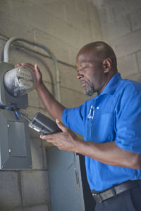 Man outdoors reading a electric meter.