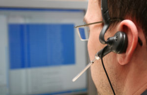 Man working at computer with headset on.