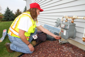 Technician checking meter's pipes outside.