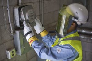 Man with face mask inspecting electric meter